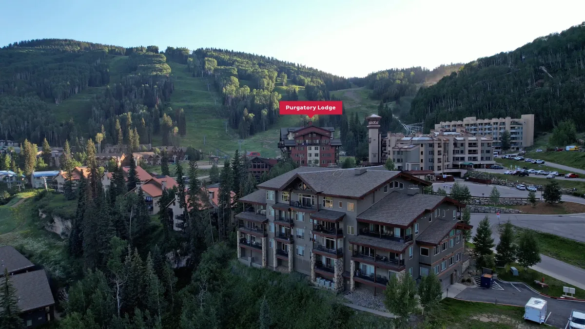 An inviting view of Purgatory Lodge set against the backdrop of tree-lined mountains. The lodge appears welcoming, emphasizing both the proximity to nature and central location. The scene hints at the easy access to outdoor activities and the cozy retreat awaiting after a day of exploration.